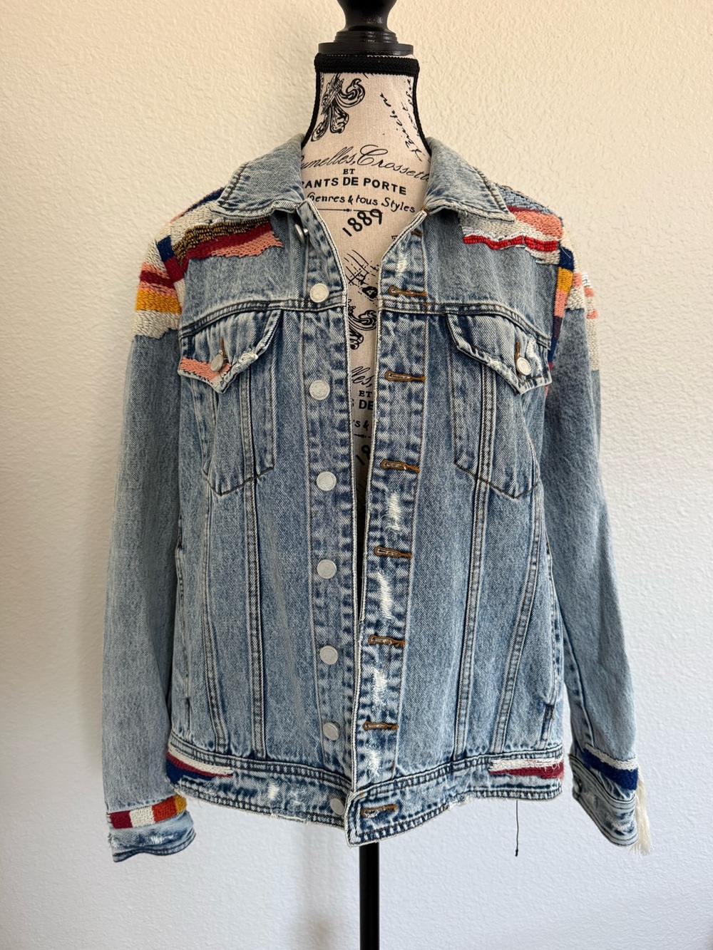 Blank NYC Light Wash Denim Jacket with Multicolor Woven Fringe Design